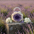 Handmade cream and purple crochet rose handbag with clear acrylic handles and purple tassel, displayed on a stone surface in a Provence lavender field with white roses by Victorian Velvet