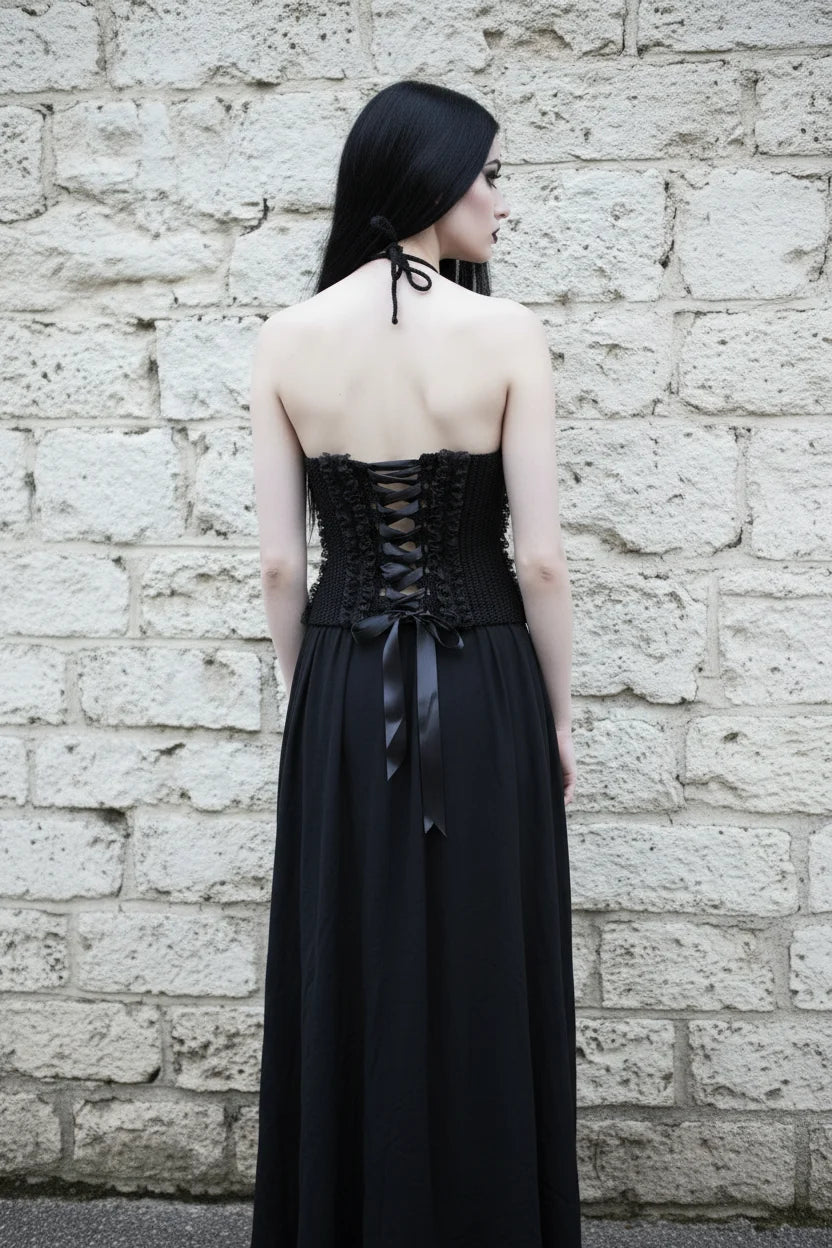 Cathedral Lace Corset – pale gothic model in full length black outfit, back view showing lace-up corset and long black skirt, weathered stone wall background, handmade gothic crochet top - Victorian Velvet