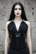 Cathedral Lace Corset – front view, pale gothic woman with long black hair and dark red lips, black handmade crochet halter corset with gathered lace and satin bows, stone wall background - Victorian Velvet