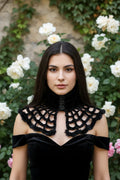 Black fluffy velvet spiderweb crochet collar with three rose buttons, worn by a dark-haired woman in a black off-shoulder velvet dress, white rose garden background - Victorian Velvet