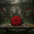 Handmade red crochet rose handbag with black handles and black leaf details, displayed on a mossy stone bench surrounded by red roses and ivy in a gothic garden - Victorian Velvet