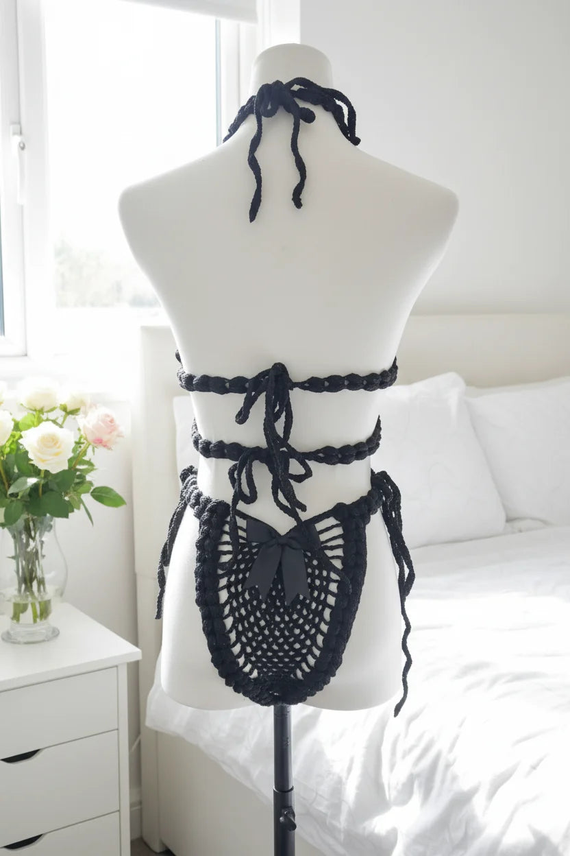Handmade black crochet lingerie set with black satin bows, back view on dress form mannequin, bright bedroom with white linen and pink roses - Victorian Velvet