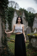 Moonlight Halter Top Silver — handmade silver crochet halter crop top, front view, gothic cemetery setting with ivy and stone monuments - Victorian Velvet