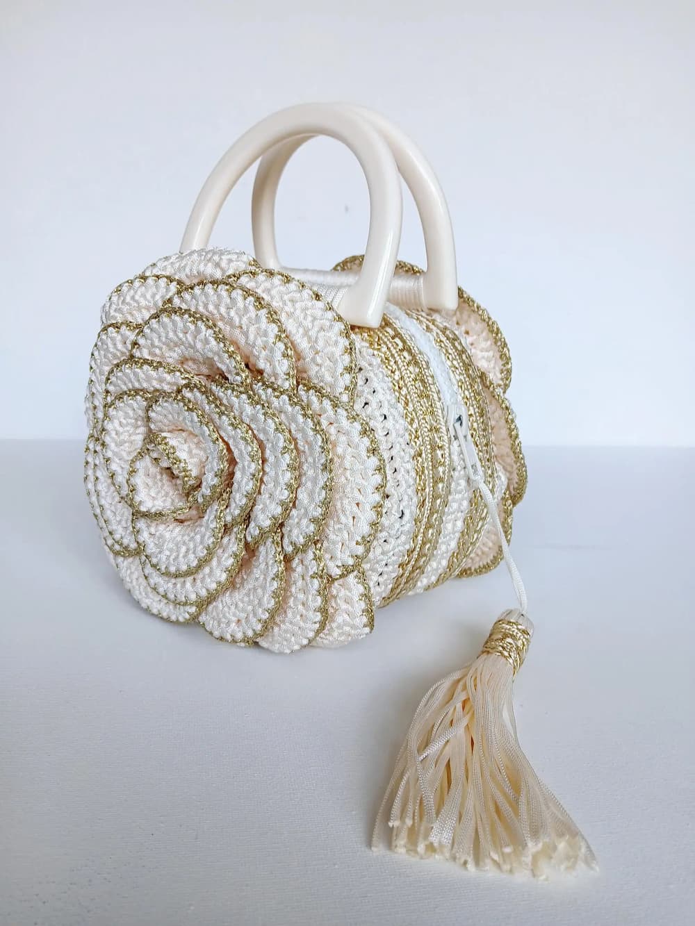 Versailles Rose handmade crochet rose handbag side view showing cylindrical body with gold metallic stripes and rose petals — Victorian Velvet
