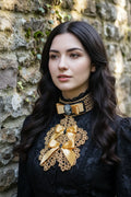 Handmade gold crochet jabot with gold satin bows and grey cameo brooch on black velvet choker, worn over a black Victorian high neck blouse, close-up portrait - Victorian Velvet