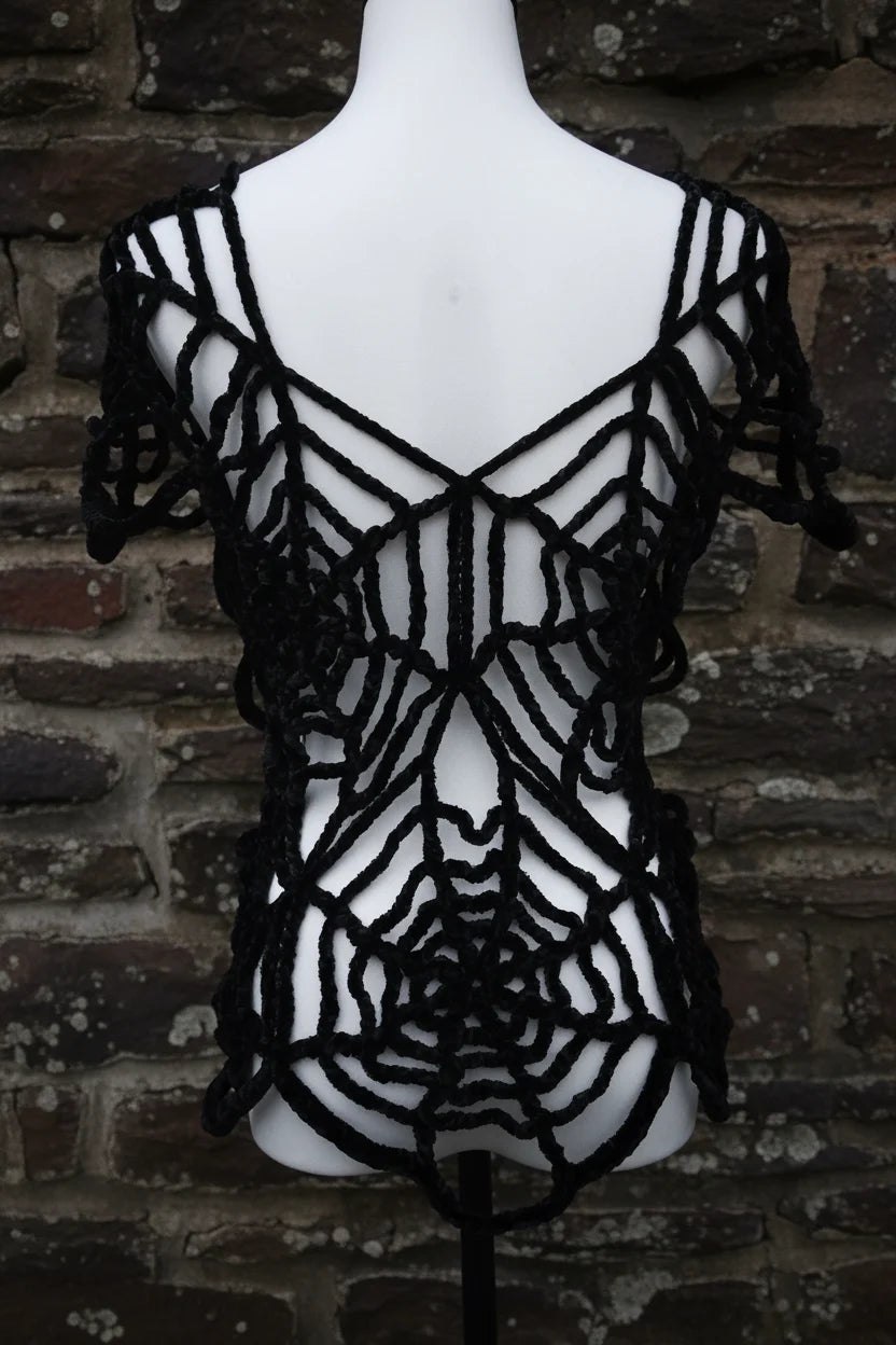 Gothic Spider Web Crochet Top on mannequin – back view showing full spider web pattern and short sleeves, handmade black crochet top, stone wall background - Victorian Velvet