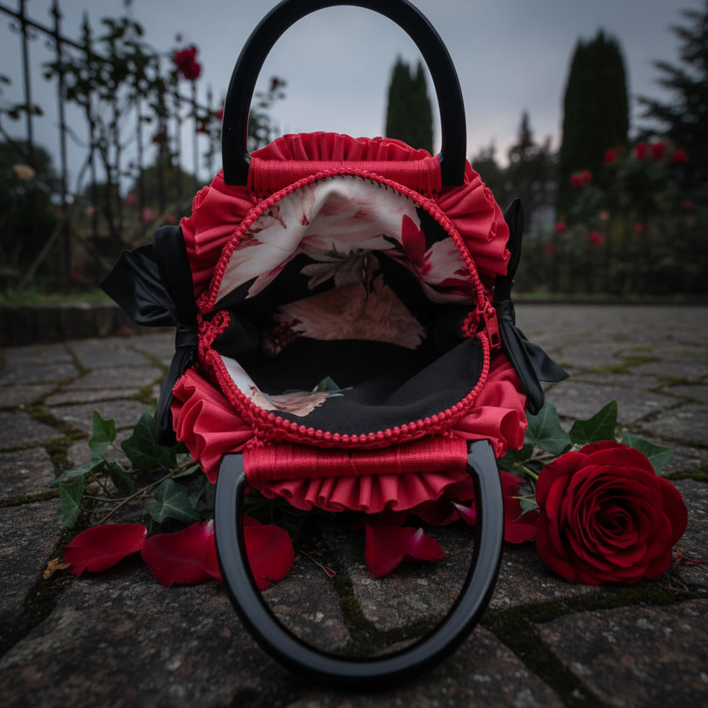 Interior view of handmade red crochet rose handbag showing floral lining, red ruffled zipper and black handles, displayed open on cobblestones with a red rose - Victorian Velvet